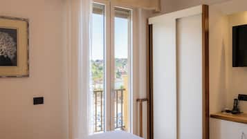 A bedroom with a bed, a sliding door to a balcony, a framed picture on the wall, and a mounted phone on the nightstand.