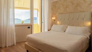 Ein Schlafzimmer mit einem großen Bett, einem fenster mit Vorhängen, einem Kopfteil mit einer Lampe und einer Wand mit Muster.