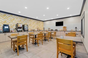 A modern restaurant with wooden tables and chairs, a counter with a menu display, and a TV mounted on the wall. - City Express By Marriott Manteno (Manteno)
