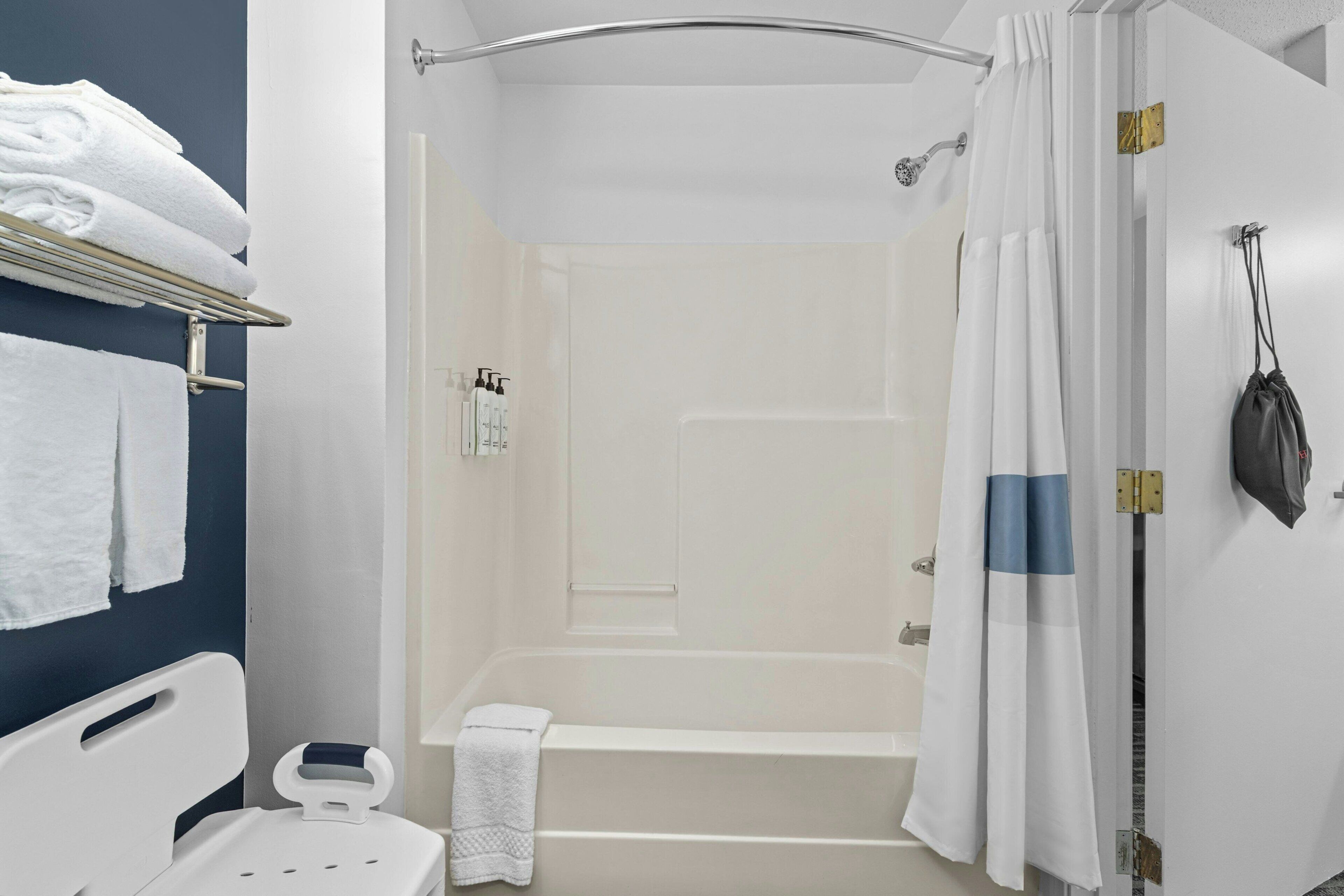 A bathroom with a bathtub, shower, and a towel rack with towels.