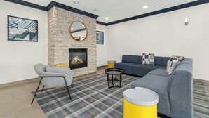 Una sala moderna con chimenea, un sofá, un sillón y un espejo redondo.