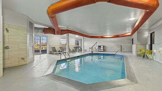 Una piscina interior con una vista despejada del techo, las paredes y un área de estar con sillas.
