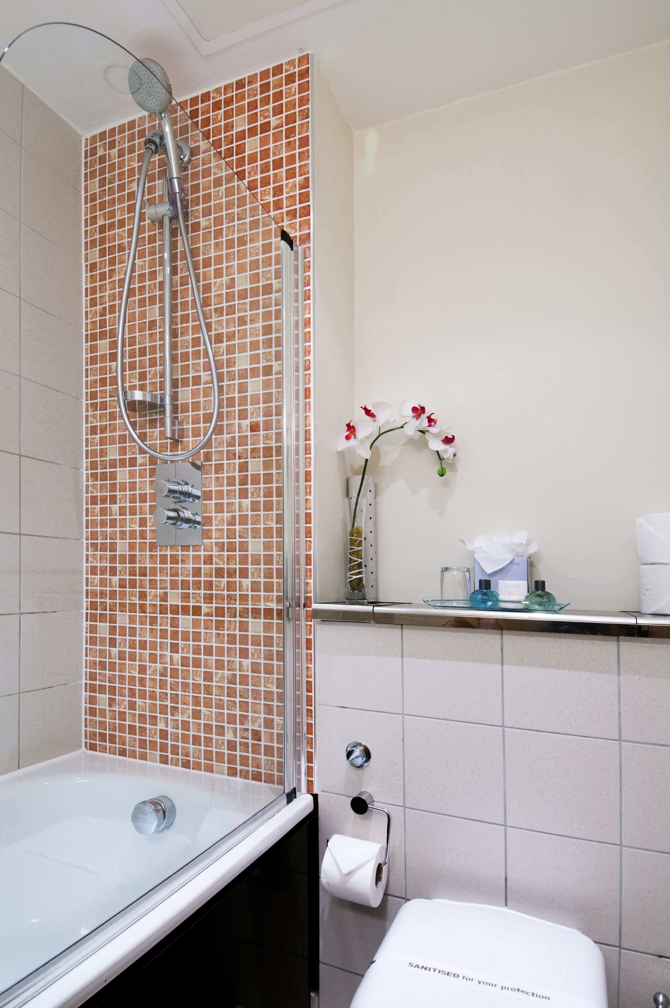 A bathroom with a glass-enclosed shower, a toilet, and a sink.