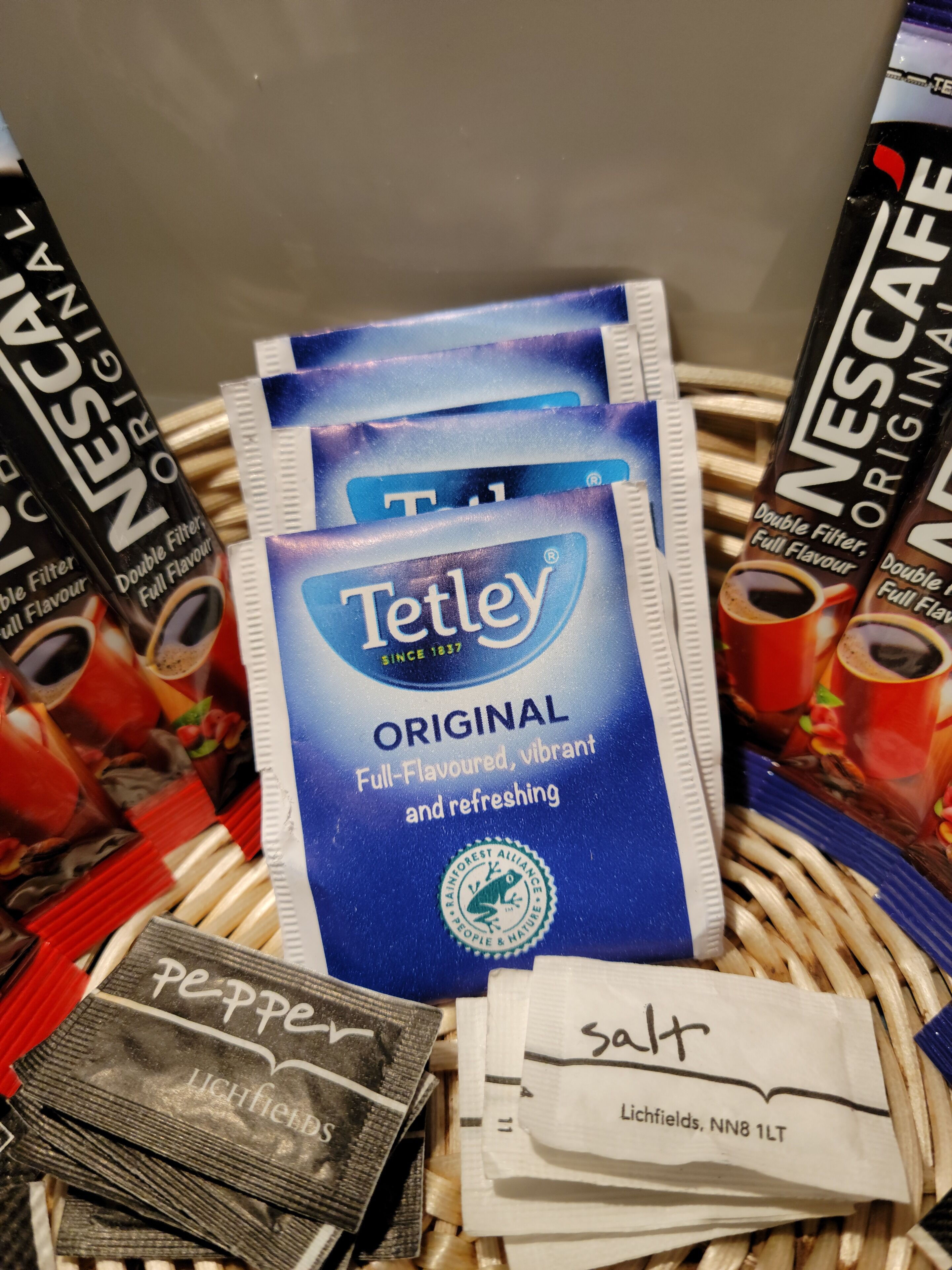 A display of Tetley Original tea bags, Lichfield salt packets, and Nescafé Original coffee capsules.