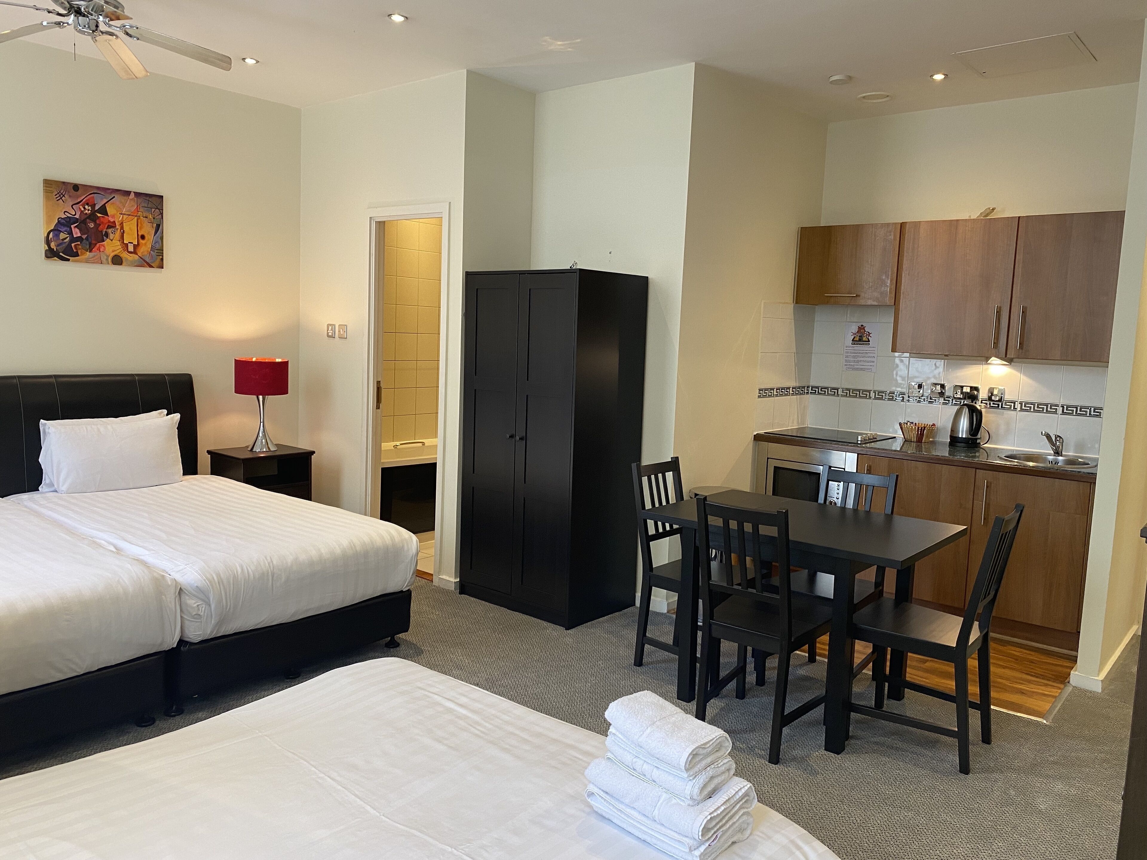Une chambre d’hôtel avec un lit, un bureau et une kitchenette.