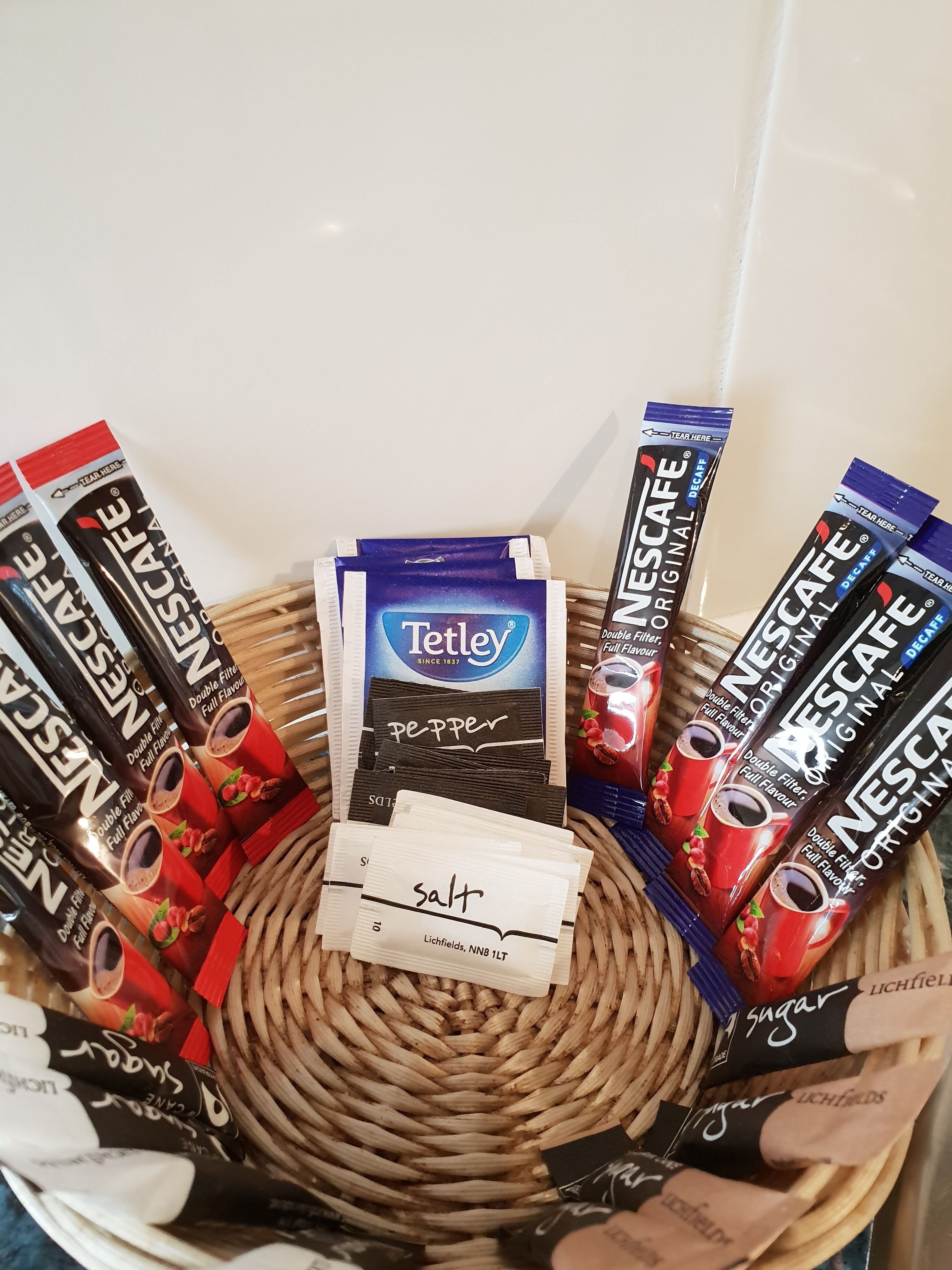 Een mandje met verschillende Nescafé zakjes, een pak Tetley thee en een zoutje.