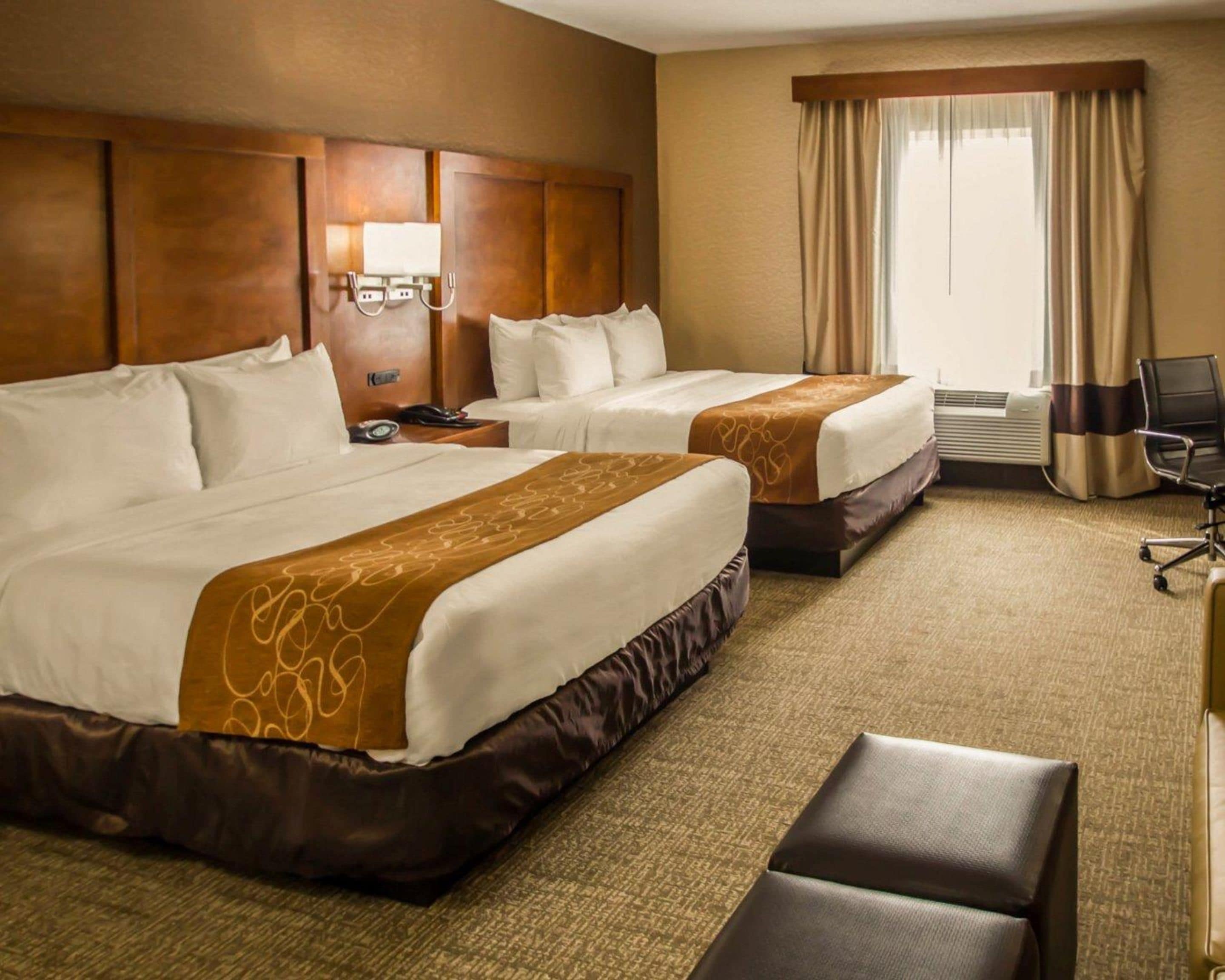 Ein Hotelzimmer mit zwei Betten, einem Schreibtisch, einem Stuhl und einer Klimaanlage.
