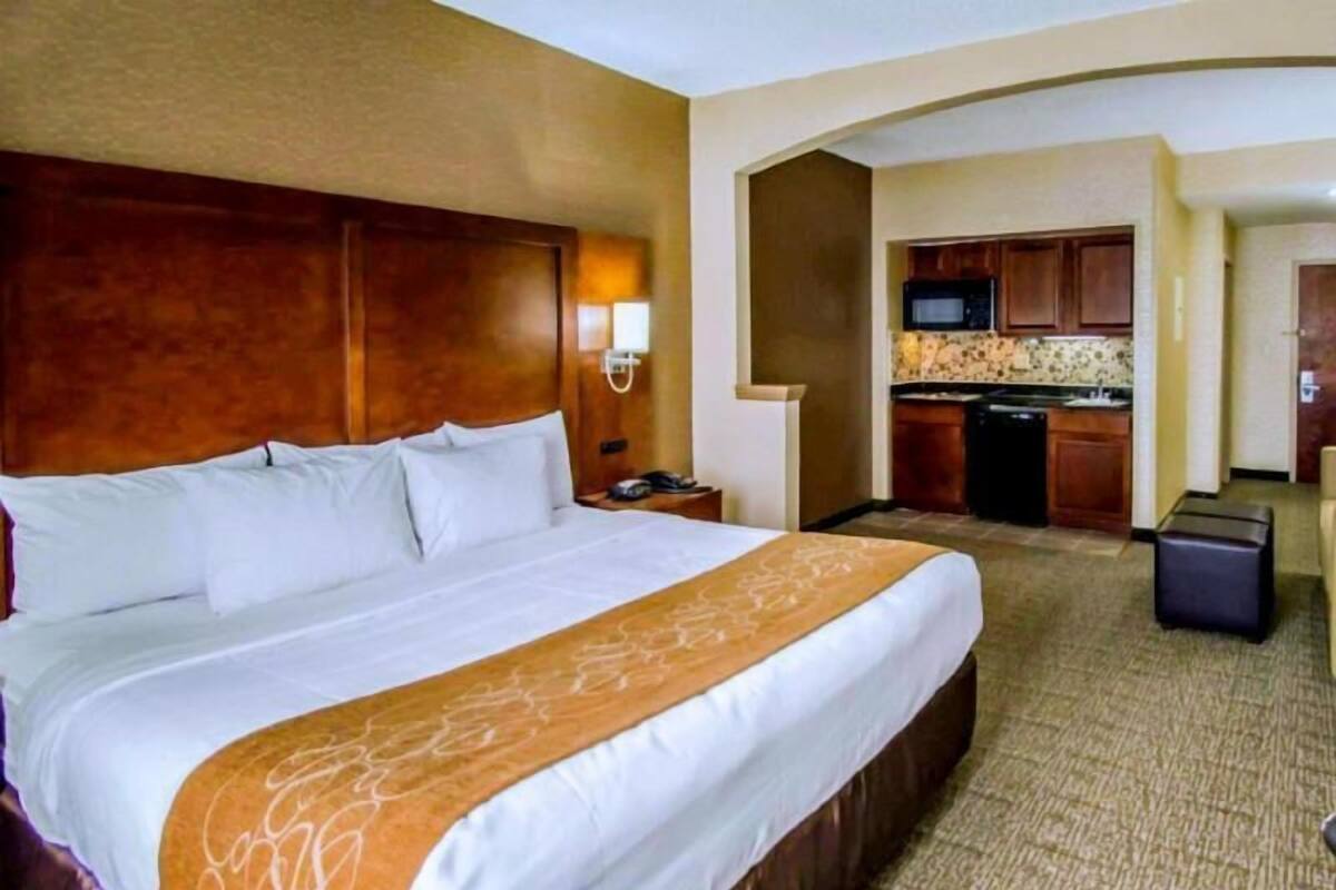 Een hotelkamer met een groot bed, een bureau, een magnetron en een kitchenette.