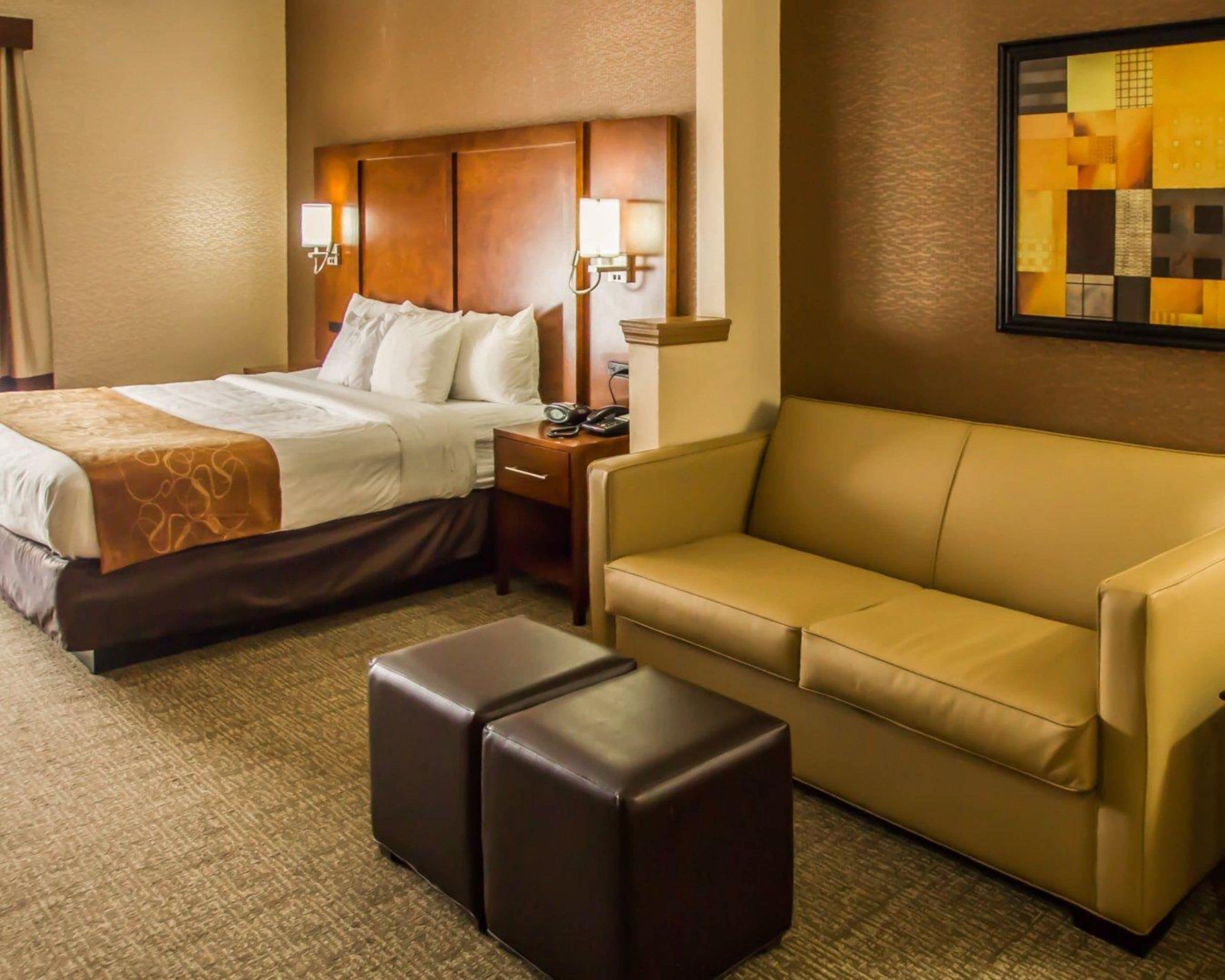 A hotel room with a bed, a sofa, and a small table.