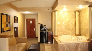 Un baño de hotel con lavamanos de mármol, una bañera grande y una pequeña kitchenette.