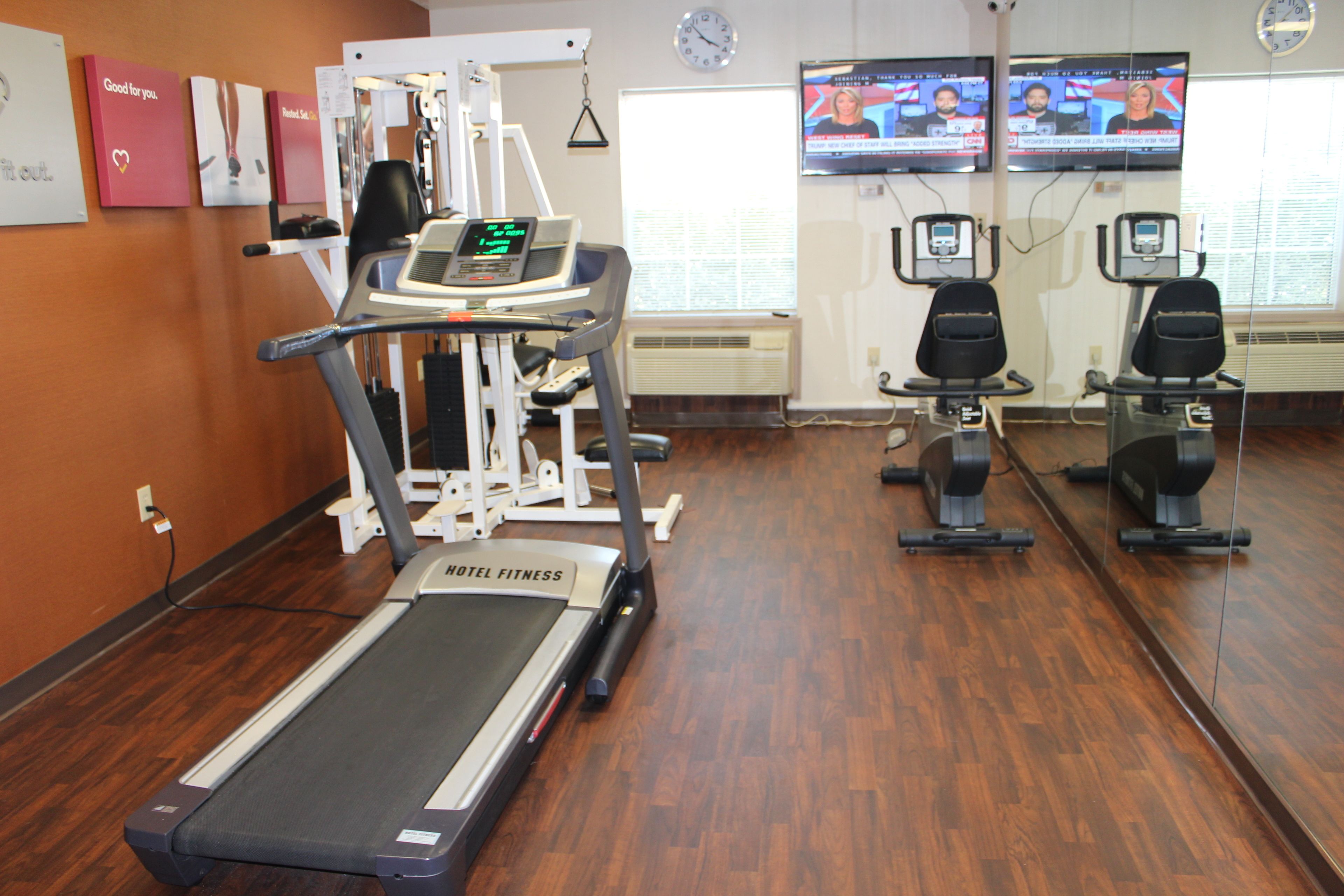 A hotel fitness center with a treadmill, weight machines, and exercise bikes.