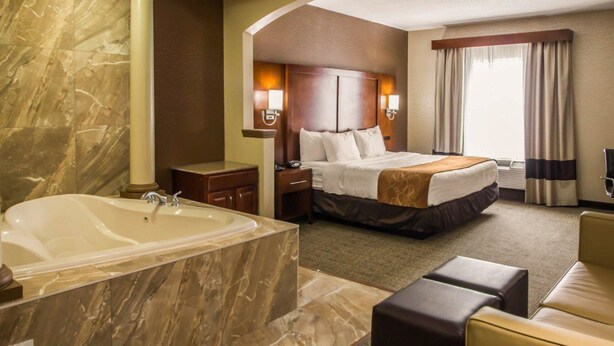 Habitación de hotel con un amplio baño de mármol, una cama tamaño king, una sala de estar y vistas a la ciudad.