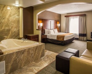 Een hotelkamer met een ruime marmeren badkamer, een extra groot bed, een zithoek en uitzicht op de stad.