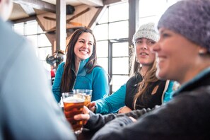 A group of people sitting at a table in a room with large windows and a high ceiling. - Panorama Mountain Resort - Ski Tip Tamarack Condos (Panorama)