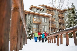 A multi-story building with balconies and a wooden fence in the foreground. - Panorama Mountain Resort - Ski Tip Tamarack Condos (Panorama)