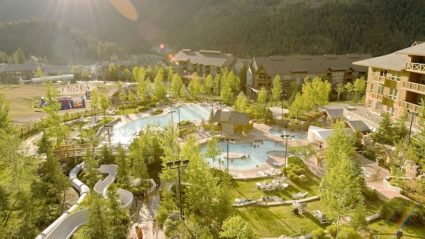 Een resort met meerdere zwembaden, een waterpark en een bergachtige achtergrond.