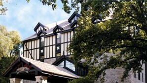 Un bâtiment historique doté d’une façade en pierre, d’un porche et d’une petite cascade dans le jardin.