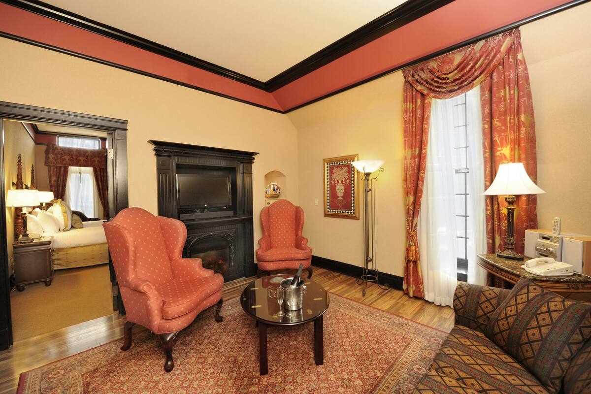 Een klassieke woonkamer met een open haard, twee fauteuils, een bank en een salontafel.