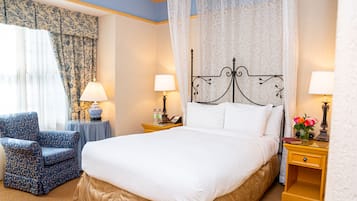 Une chambre d’hôtel avec un grand lit, deux tables de chevet avec des lampes, une chaise et une fenêtre avec des rideaux.