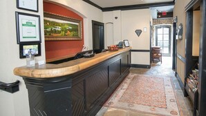 Un espace d’accueil avec un comptoir en bois, des certificats encadrés et un tableau au mur.