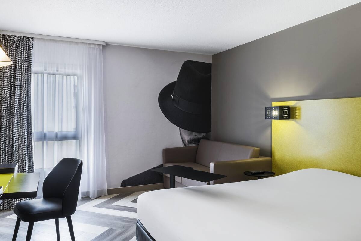 Una camera d'albergo moderna con un letto, una scrivania, una sedia e un divano.