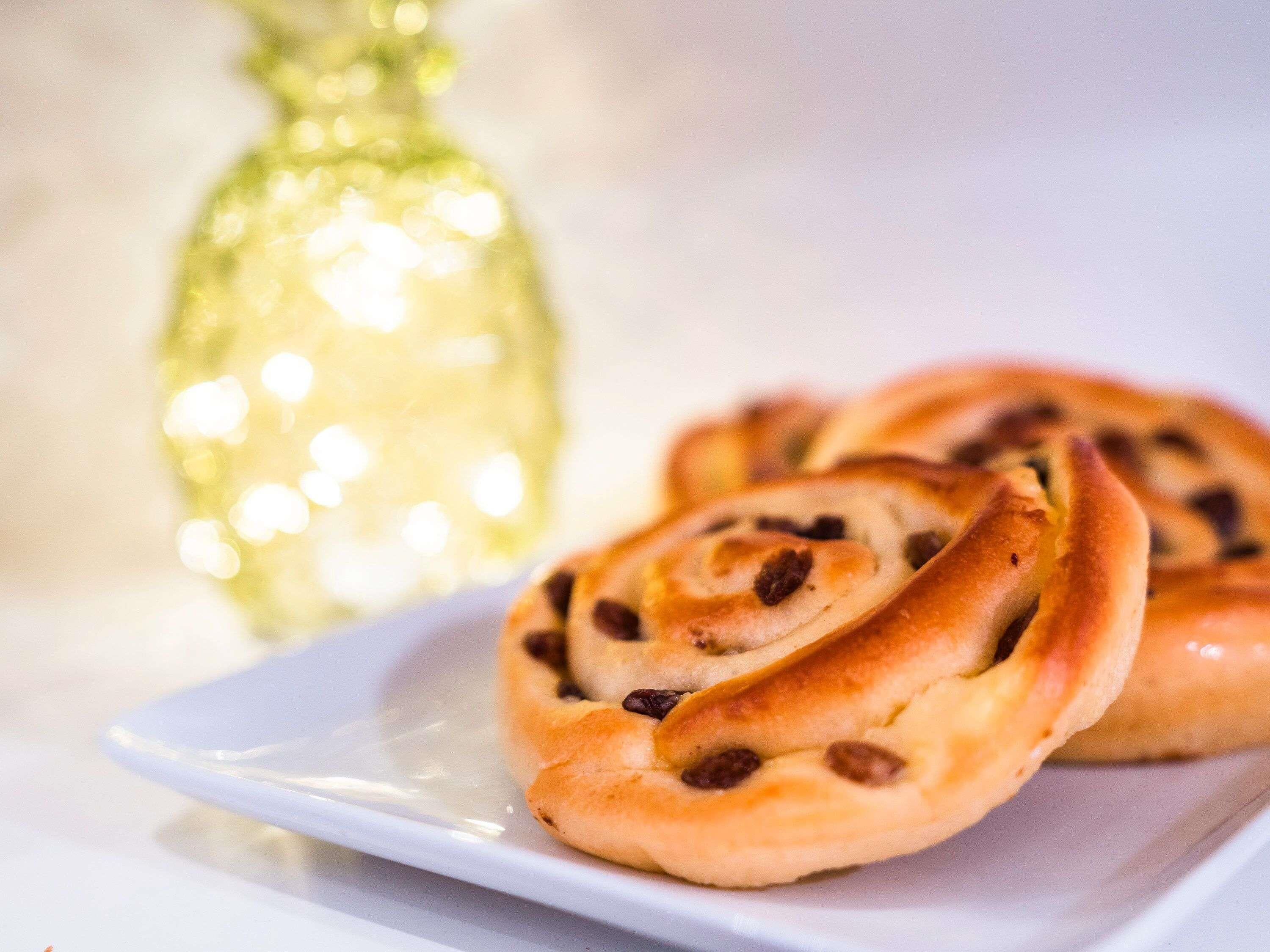 A plate of cinnamon rolls with raisins on a white plate.
