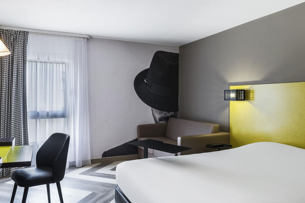 Quarto de hotel moderno com uma cama, uma escrivaninha, uma cadeira e um sofá.