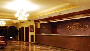 Un vestíbulo de hotel con mostrador de recepción, candelabro y área de registro.