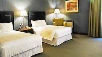 A hotel room with two beds, a nightstand, a lamp, and a painting on the wall.