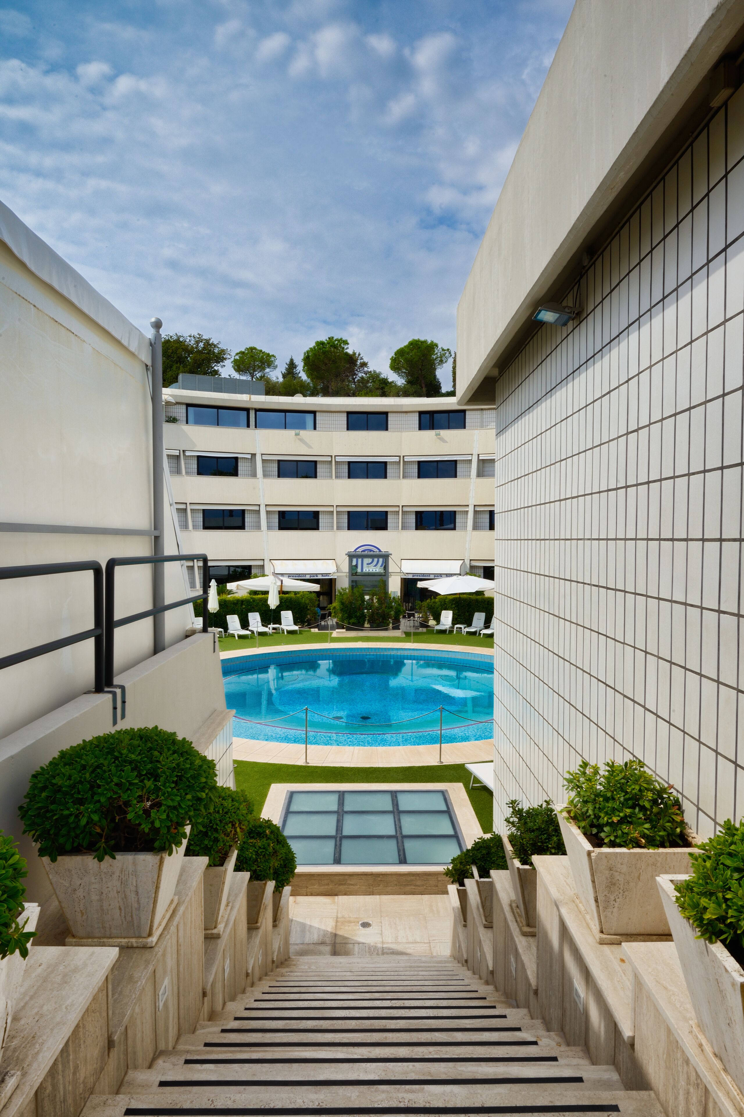 Un hotel moderno con piscina, varios pisos y vista al cielo.