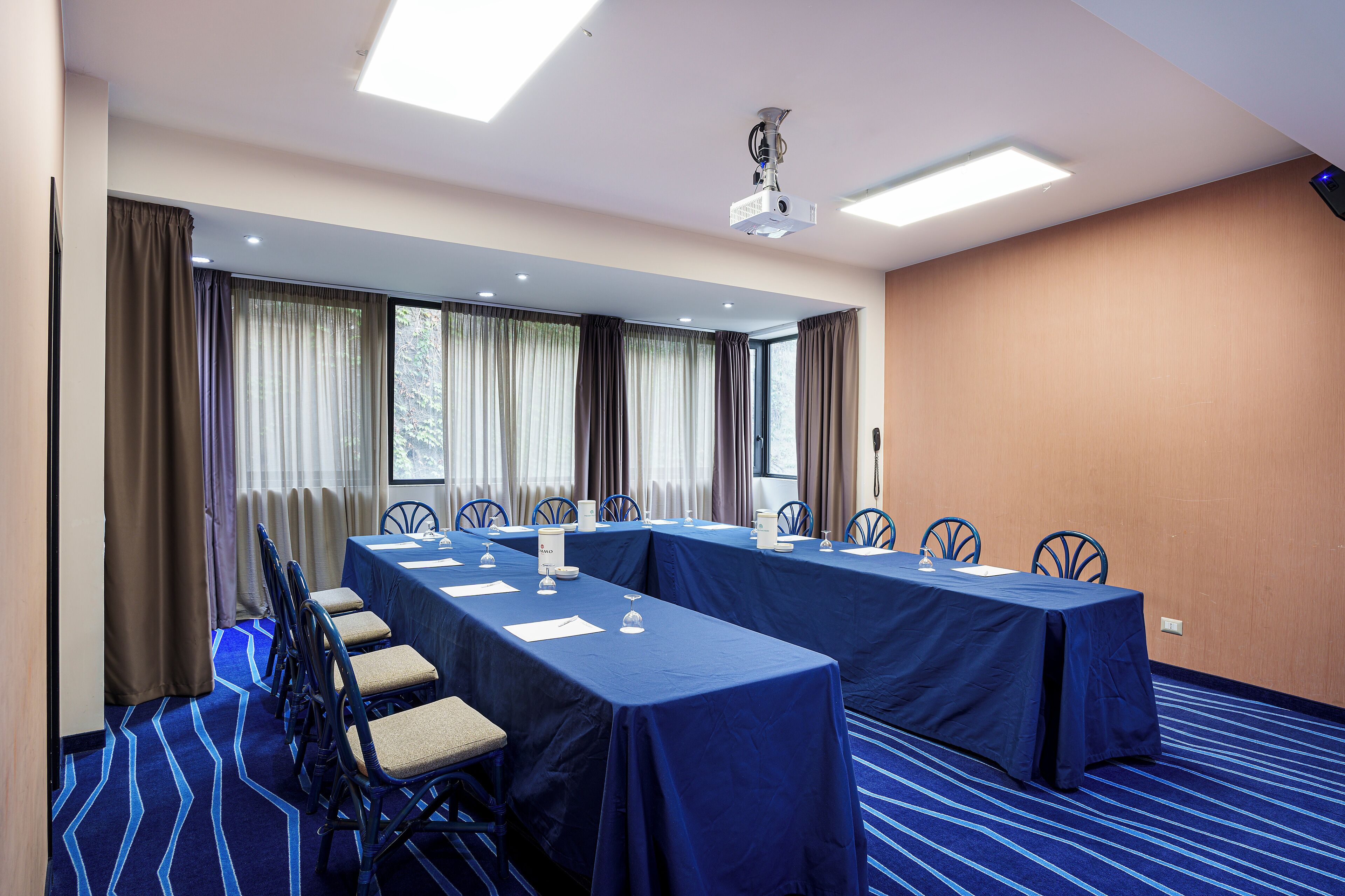 Un salón de conferencias con una larga mesa, sillas y un proyector.
