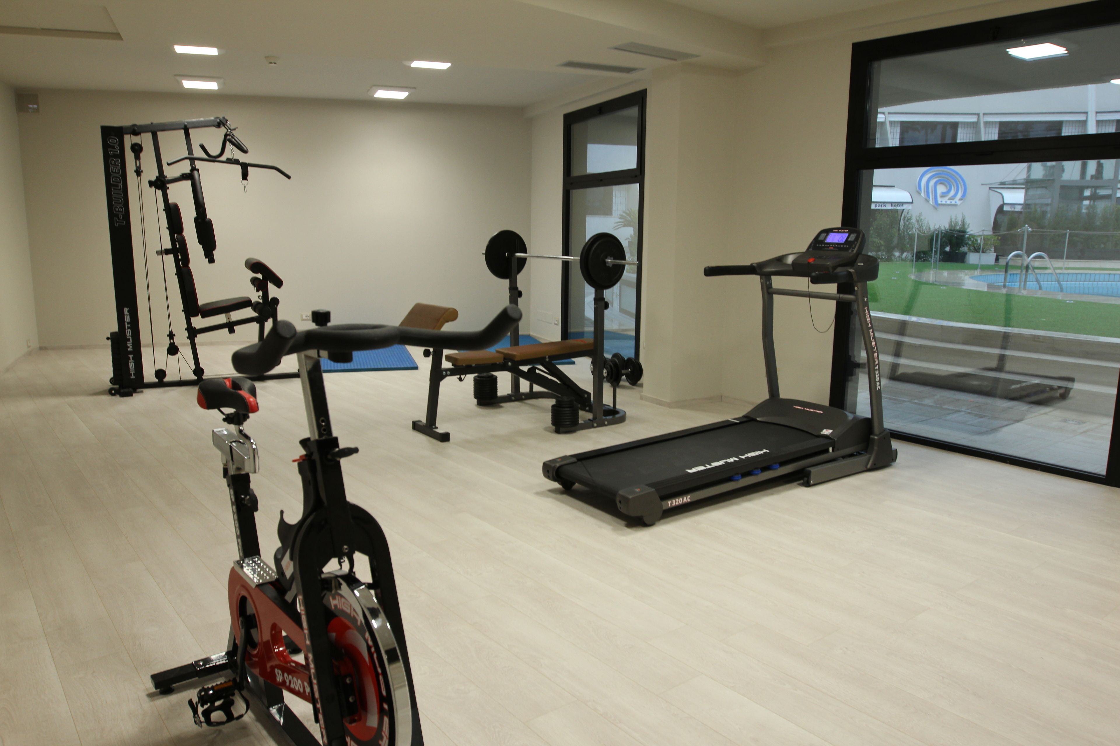 A gym with cardio equipment, weightlifting stations, and a bench.