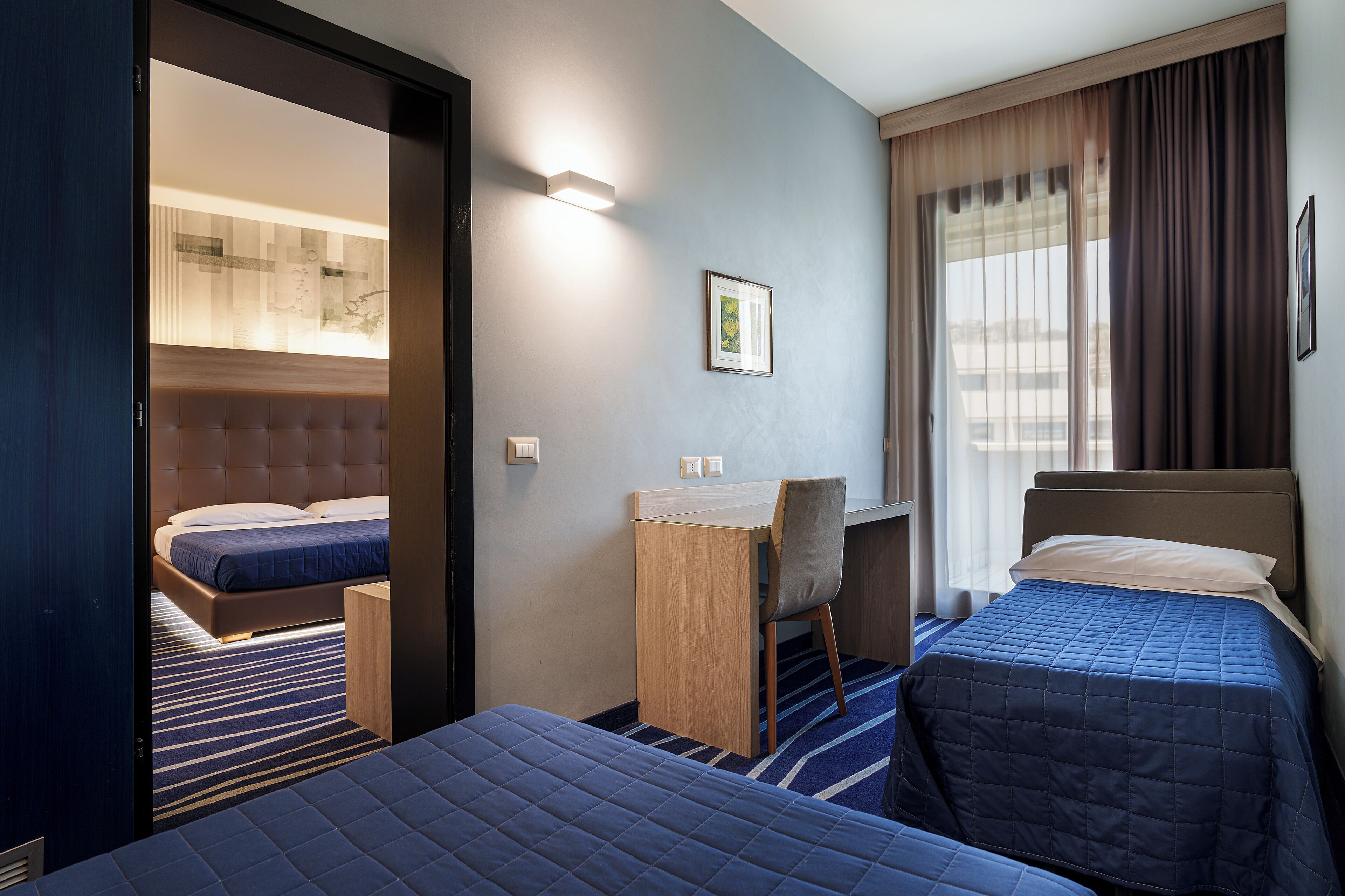 Ein Hotelzimmer mit zwei Betten, einem Schreibtisch und einem Stuhl.