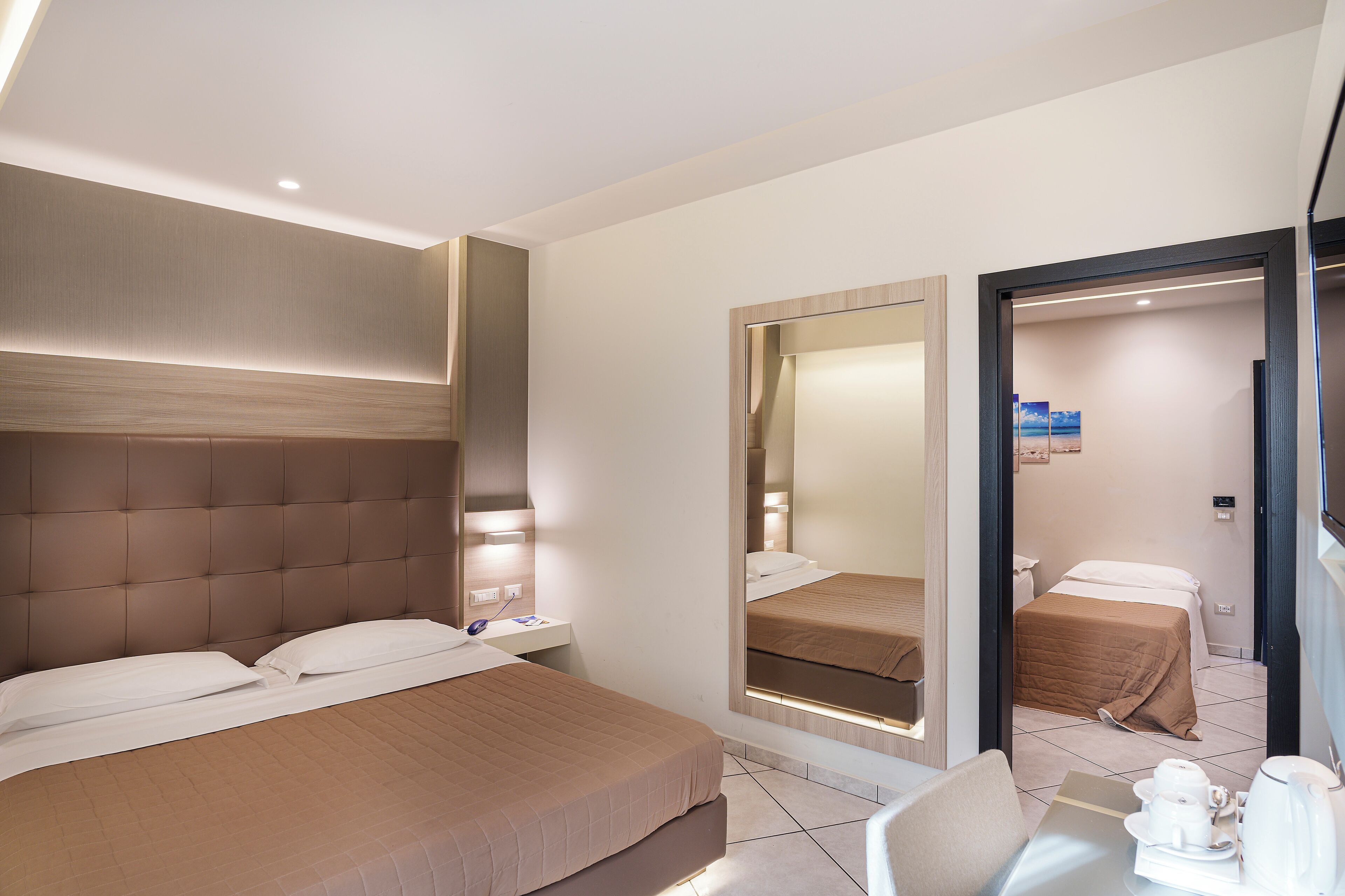 Habitación de hotel con una cama grande, una mesita de noche, una silla, un escritorio y un espejo.