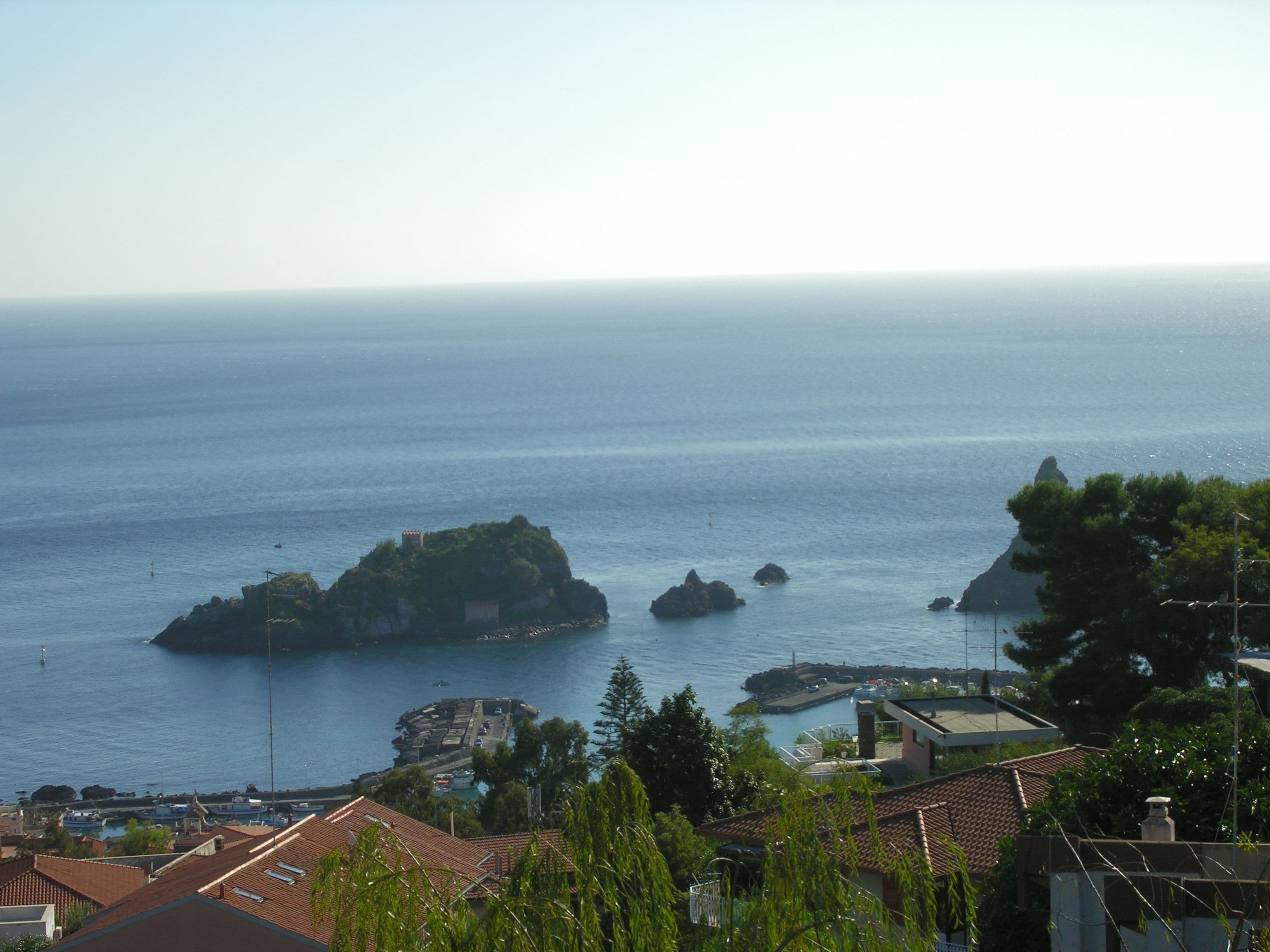 Une vue sur la côte, avec une petite île, un port de plaisance et des immeubles résidentiels.