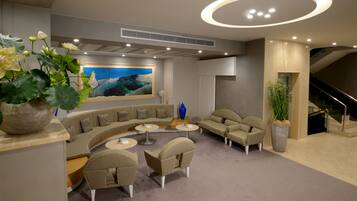 Un espace de détente moderne avec un canapé incurvé, des tables rondes et un grand tableau accroché au mur.