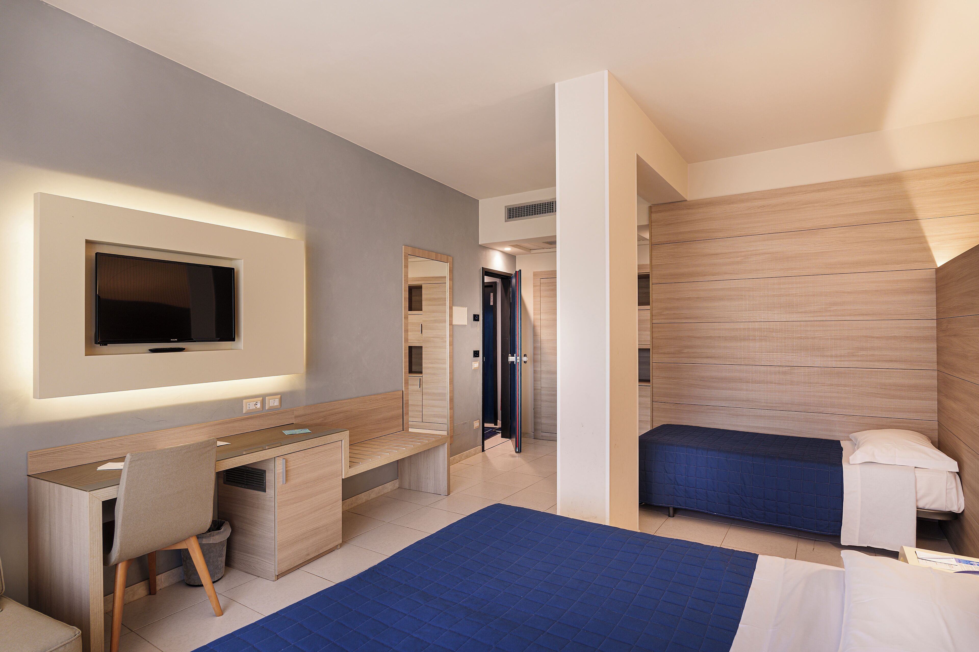 Ein modernes Hotelzimmer mit Schreibtisch, Stuhl und zwei Einzelbetten.