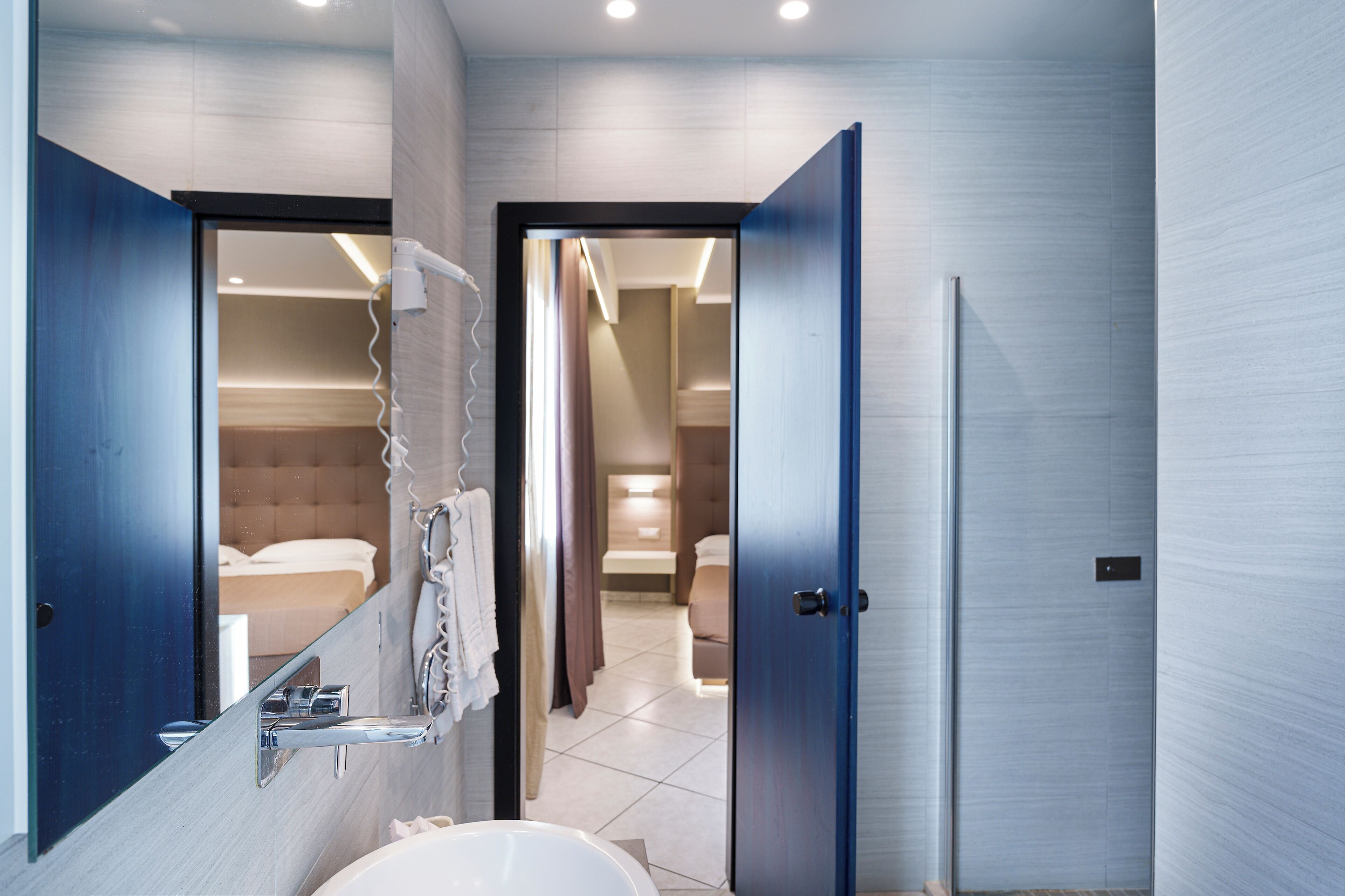 Une salle de bain moderne avec un grand miroir, un lavabo et un espace douche.