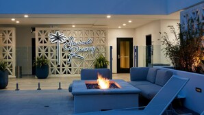 A modern outdoor seating area with a fire feature, a neon sign, and potted plants. - Courtyard by Marriott Santa Barbara Downtown (Santa Barbara)