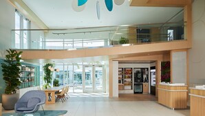 A spacious, modern lobby with a high ceiling, a central seating area, and a reception desk. - Courtyard by Marriott Santa Barbara Downtown (Santa Barbara)