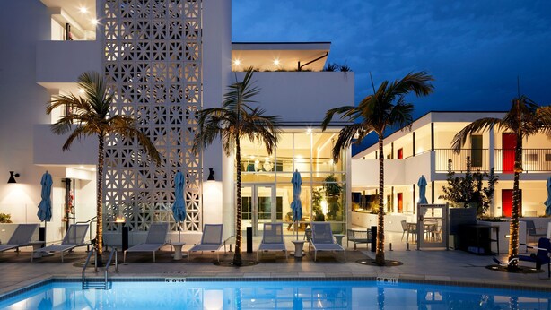 A modern hotel with a pool, lounge chairs, and palm trees. - Courtyard by Marriott Santa Barbara Downtown (Santa Barbara)