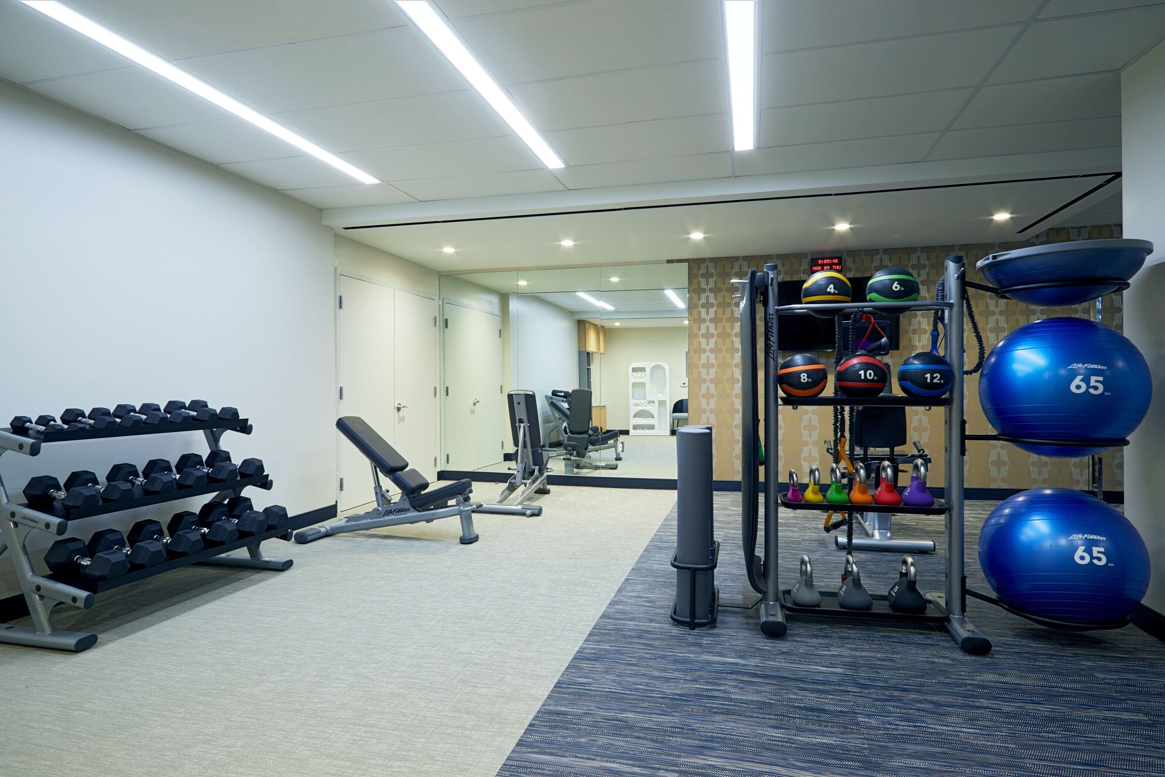 Uma academia com equipamentos de ginástica, halteres e bolas de exercícios.
