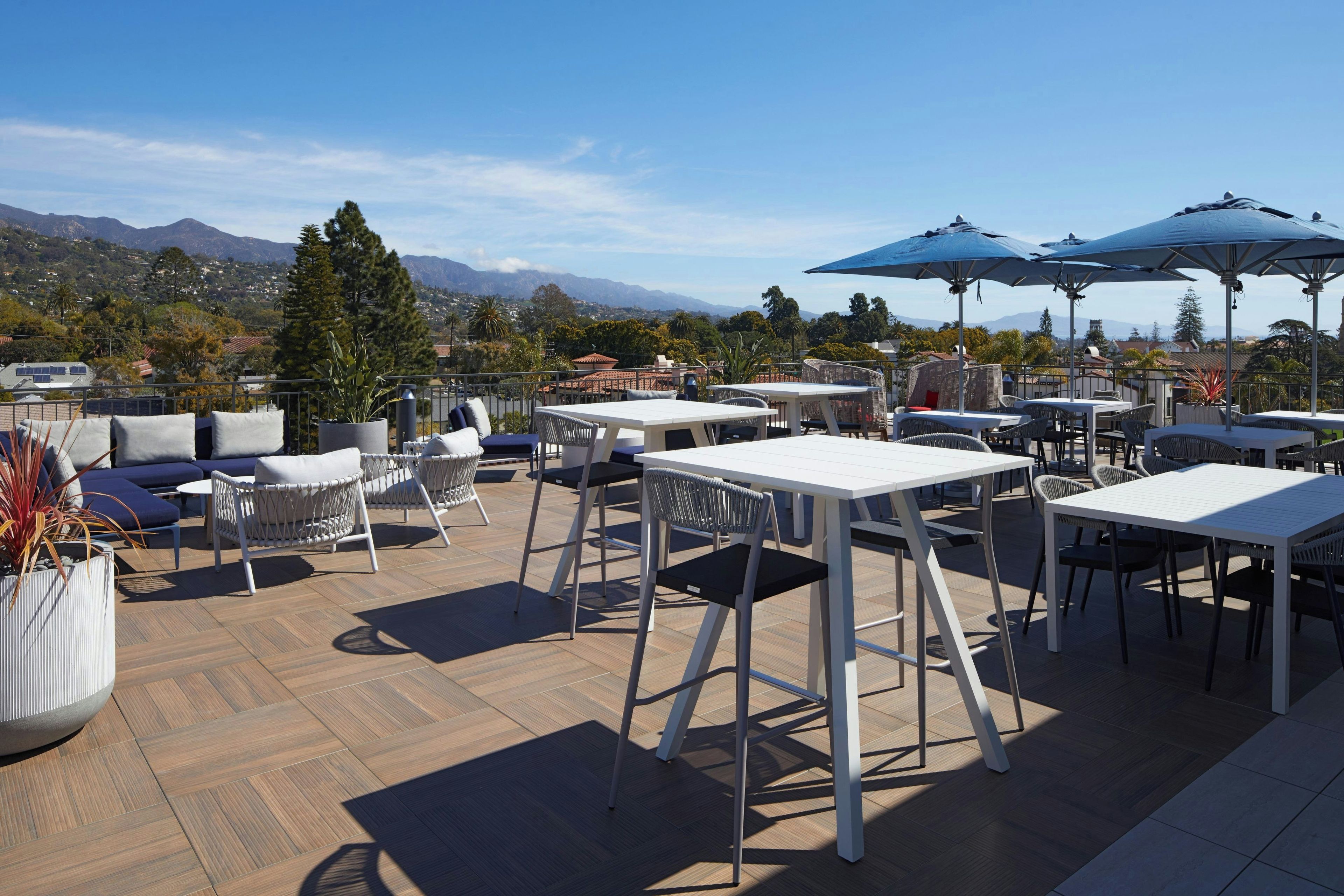 An outdoor patio area with tables and chairs, a view of mountains, and a clear sky.