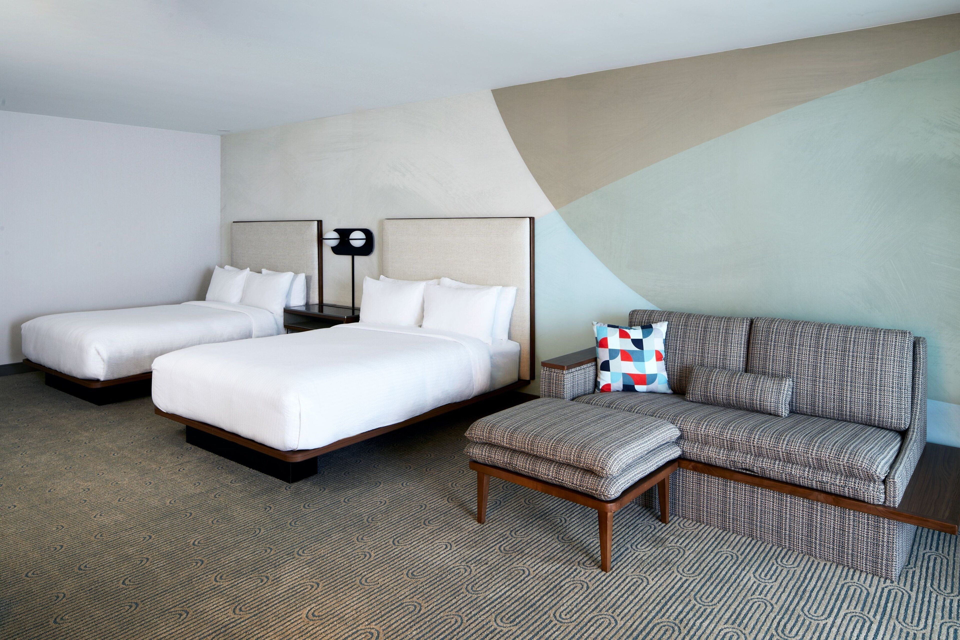 Habitación de hotel con dos camas, un sofá y una mesita.