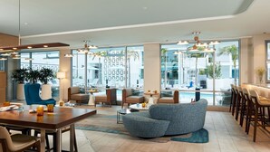 A spacious lobby with a dining area, seating arrangements, and large windows offering views of the outdoor area. - Courtyard by Marriott Santa Barbara Downtown (Santa Barbara)