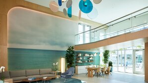 A spacious lobby with a modern design, featuring a large seating area, a dining table, and a bookshelf. - Courtyard by Marriott Santa Barbara Downtown (Santa Barbara)