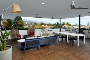 Um pátio externo com área de jantar, assentos e ventiladores de teto.