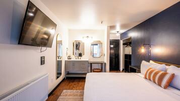 A modern bedroom with a large bed, a television, a mirror, and a wardrobe.