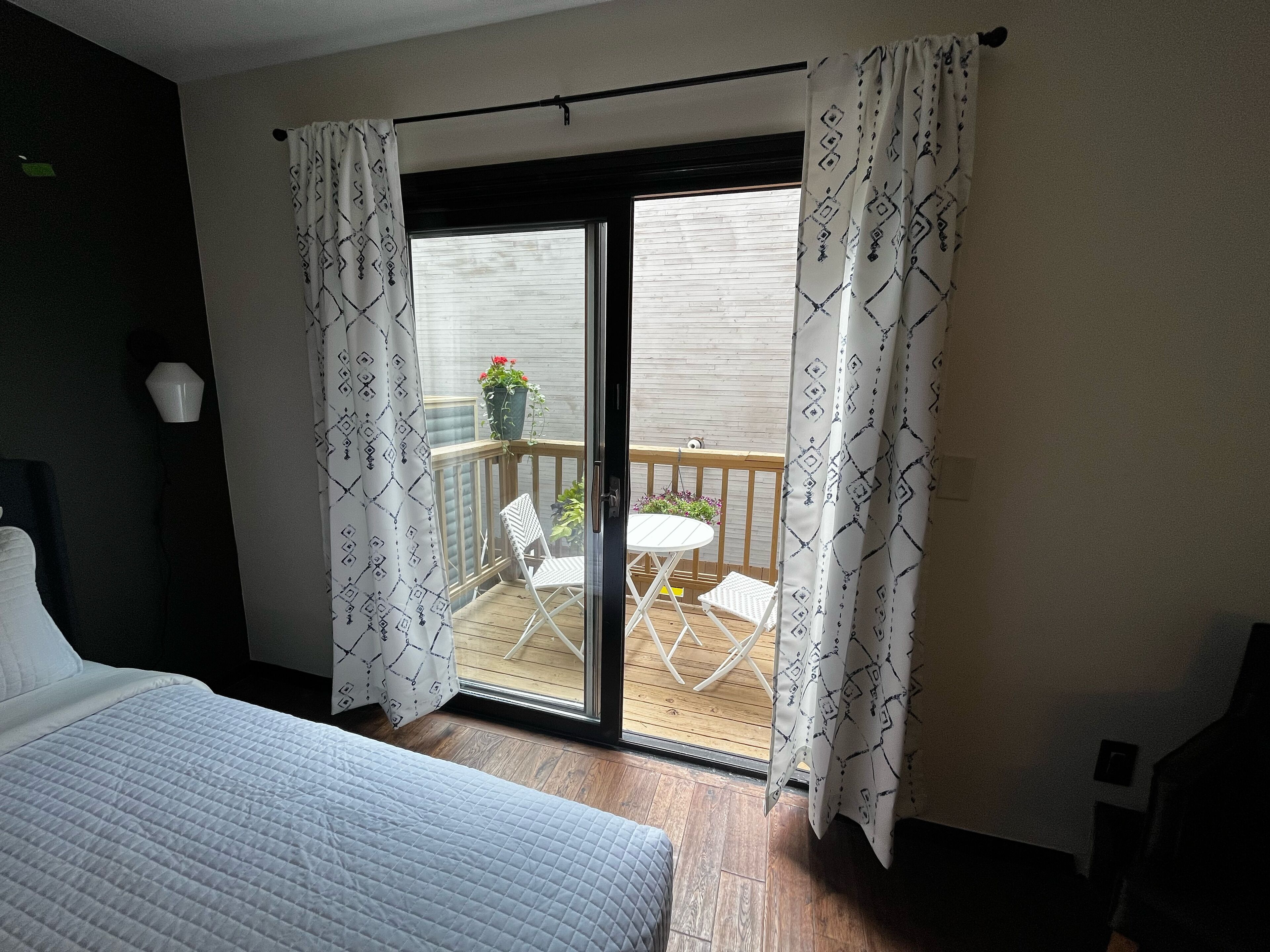 Ein Schlafzimmer mit einem Bett, einer Schiebetür zum Balkon und Blick ins Freie.