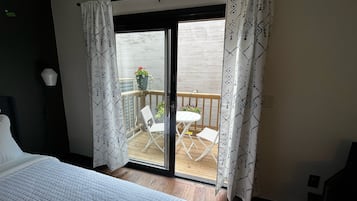 Ein Schlafzimmer mit einem Bett, einer Schiebetür zum Balkon und Blick ins Freie.